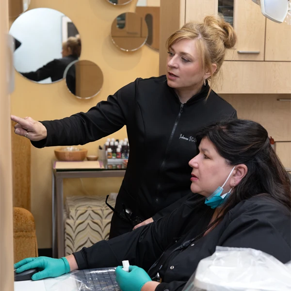 Johnna Shockley reviewing information on a monitor in a treatment room with clinical equipment nearby.