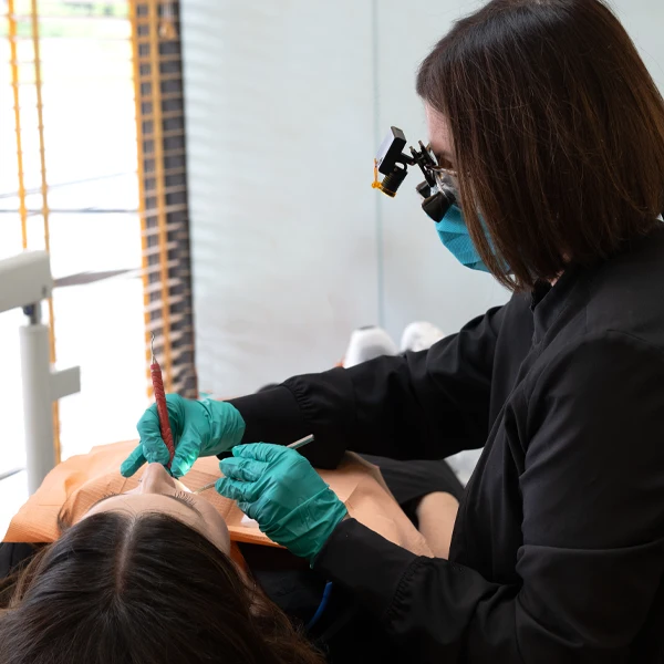 Dental professional wearing protective equipment performing a procedure on a reclining patient.